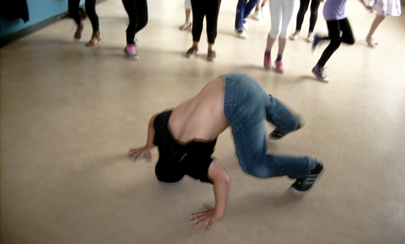 Junge tanzt Breakdance im Flur vor seinen Mitschülern.