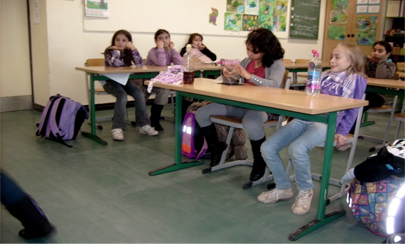 Kinder sitzen an ihren Tischen in einem Klassenraum.