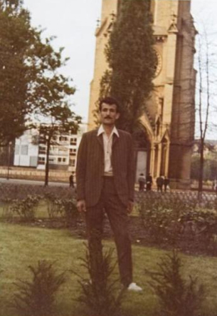 Ismael Bahadir in einem Park, im Hintergrund eine Kirche