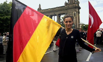 Junge Türkin mit Deutschlandfahne, im Hintergrund die türkische Fahne