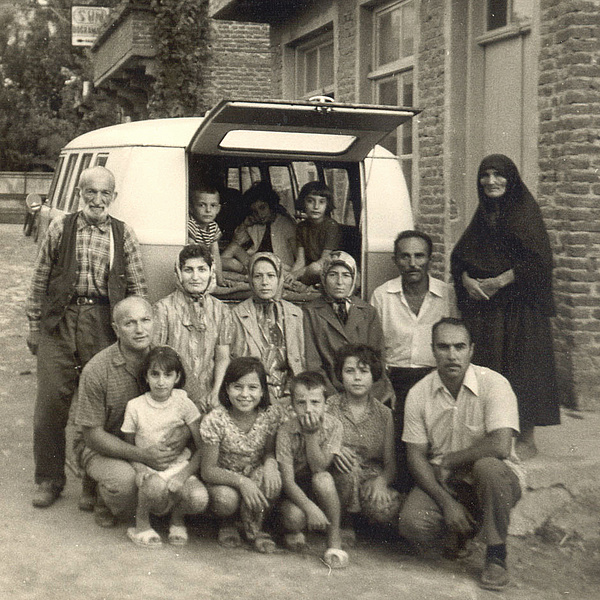 Fünzehnköpfige Familie (mehrere Generationen) "posiert" vor einem Bus